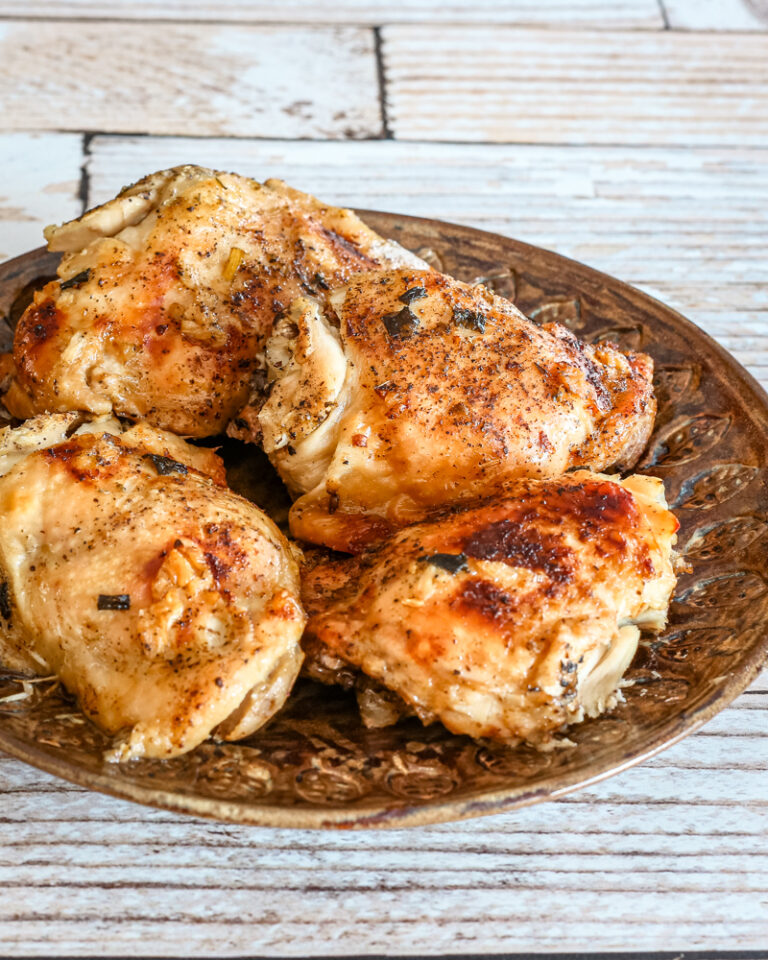 A plate of chicken thighs with lemon and garlic.