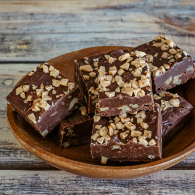 A small wood serving dish with old fashioned chocolate fudge topped with chopped nuts.