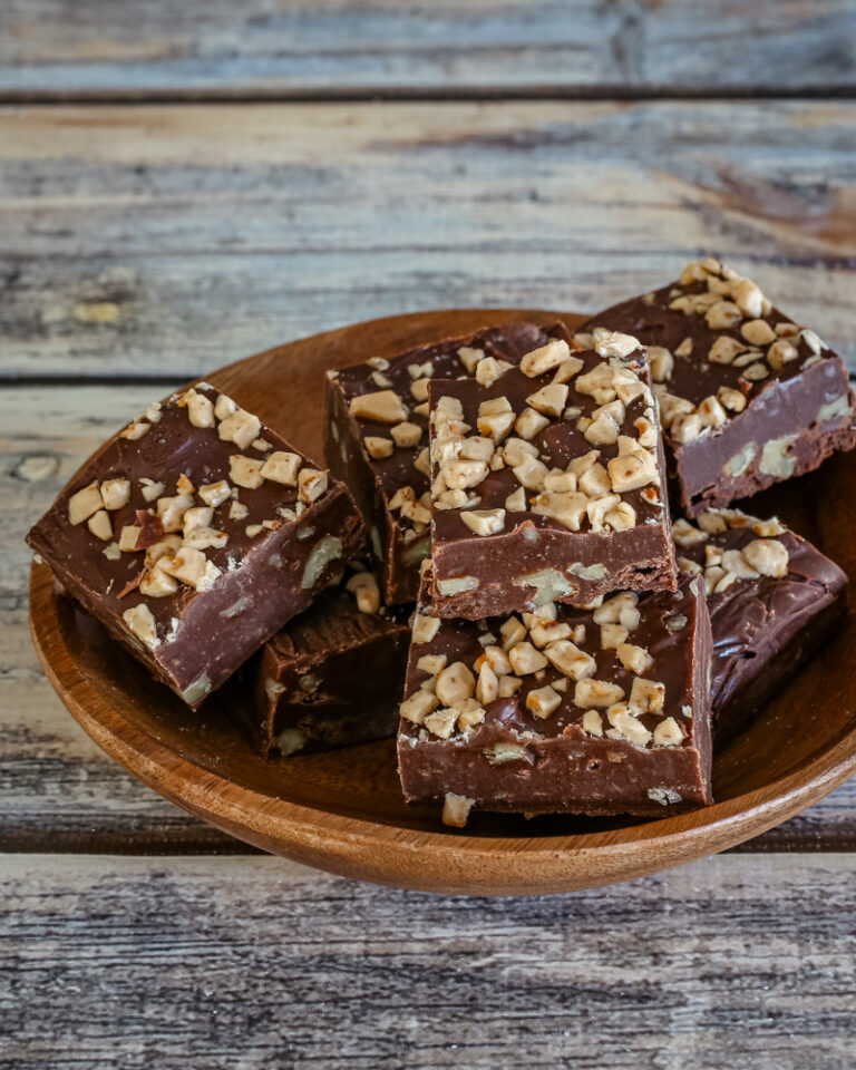 A small wood serving dish with old fashioned chocolate fudge topped with chopped nuts.