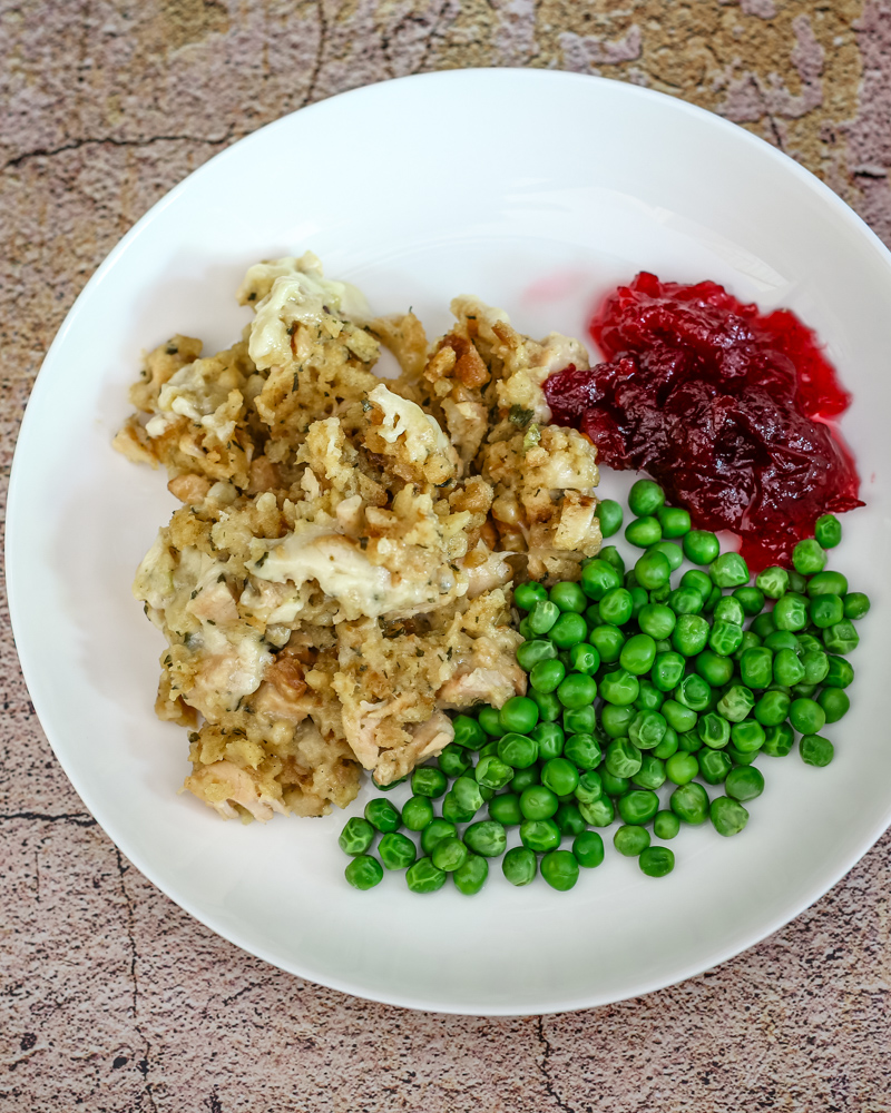Chicken and dressing portion on a plate with cranberry sauce and a small salad.
