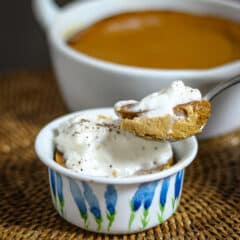 A ramekin with pumpkin pudding, showing a spoon lifting some of the pudding out.