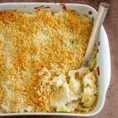 A baking dish with scalloped cabbage, served with a large spoon.