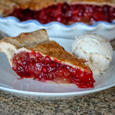 An apple cranberry pie slice on a plate.