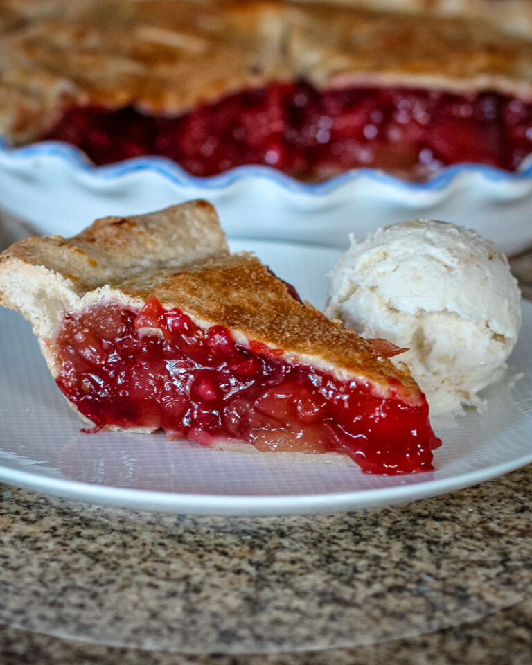 An apple cranberry pie slice on a plate.