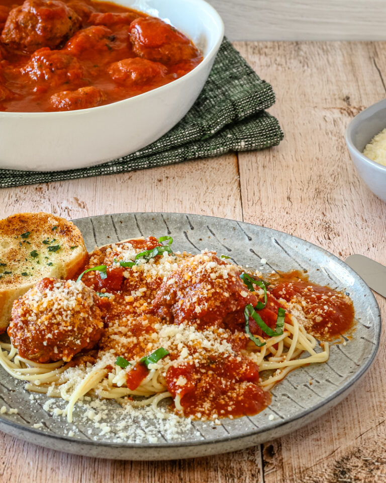 A plate of spaghetti and meatballs on a plate with Parmesan cheese.