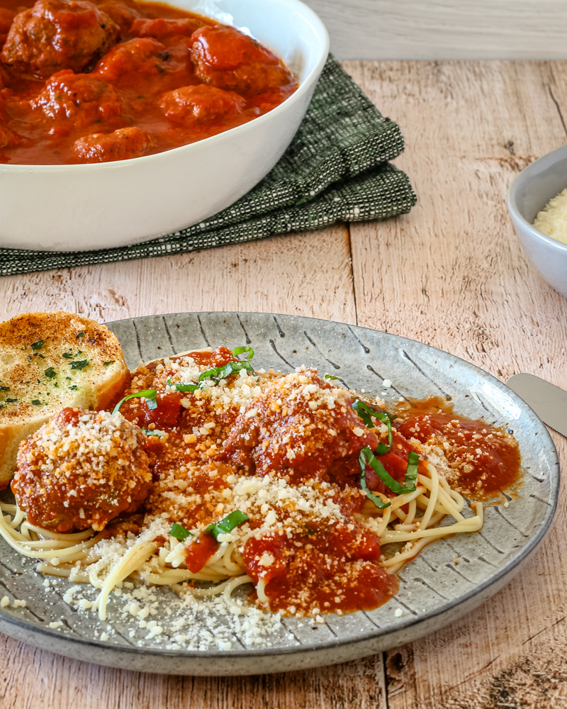 A plate of spaghetti and meatballs on a plate with Parmesan cheese.