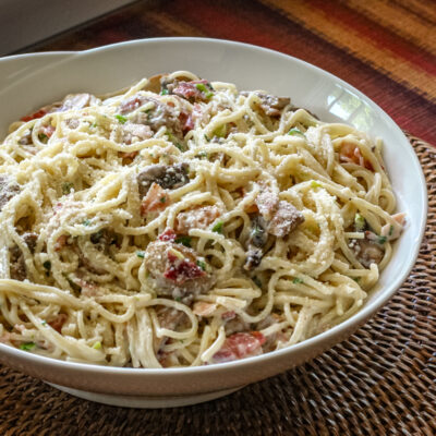 Spaghetti with bacon and mushrooms in a serving bowl
