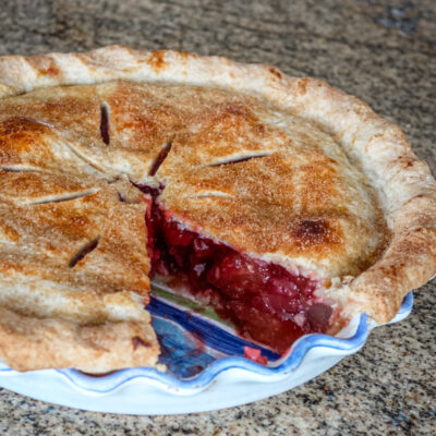 Strawberry rhubarb pie baked, with a piece cut out.