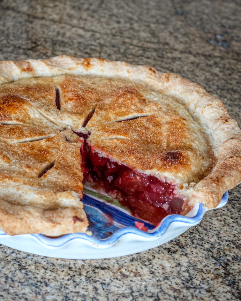 Strawberry rhubarb pie baked, with a piece cut out.