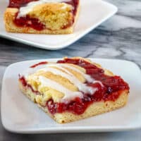 Iced cherry cobbler bars on dessert plates.