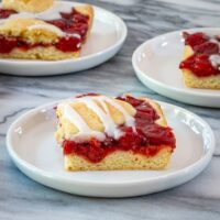 Iced cherry cobbler bars on dessert plates.