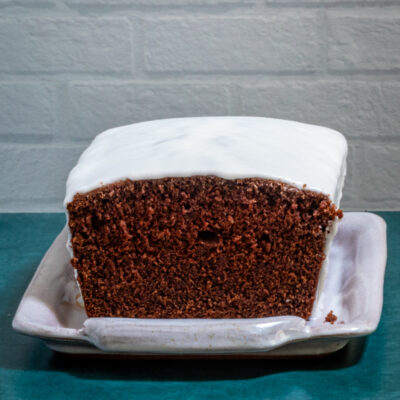 An iced chocolate loaf cake on a tray, sliced.