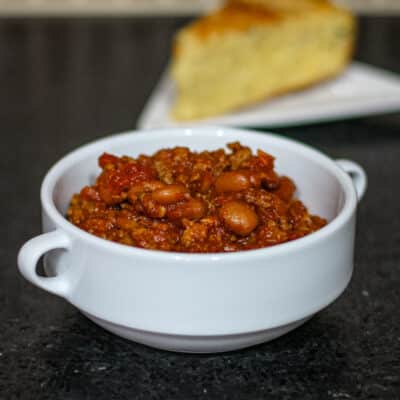 Peggy's chili in a bowl with cornbread in the background.