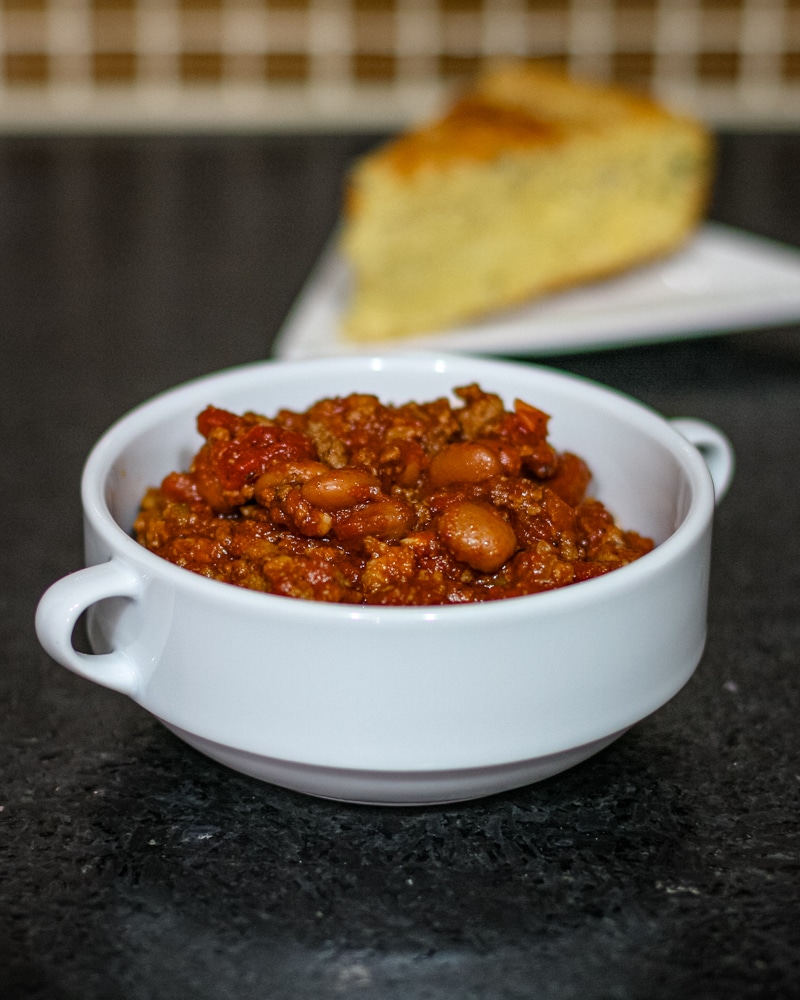 Peggy's chili in a bowl with cornbread in the background.