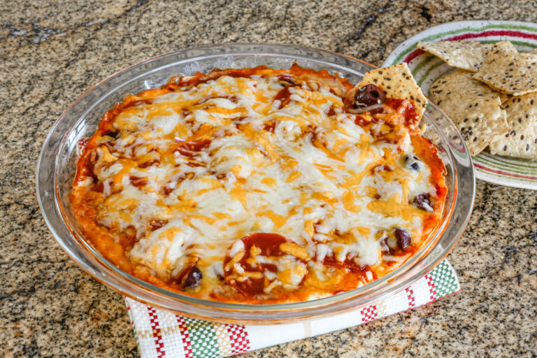 Pepperoni pizza dip baked in a pie plate with chips.