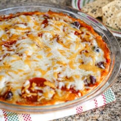 A pizza dip baked in a pie plate with melted cheese topping.