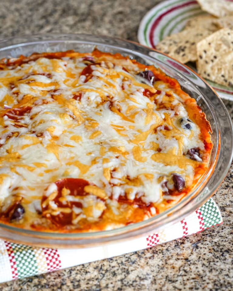 A pizza dip baked in a pie plate with melted cheese topping.