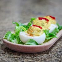 Deviled eggs on a small tray with lettuce and pimentos.
