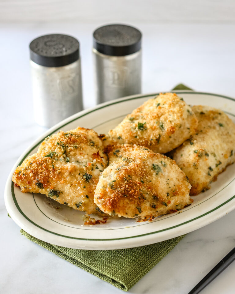 Garlic Parmesan chicken on a serving platter with salt and pepper shakers behind it.
