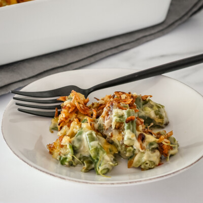 A serving of green bean casserole on a plate with a fork on the side.