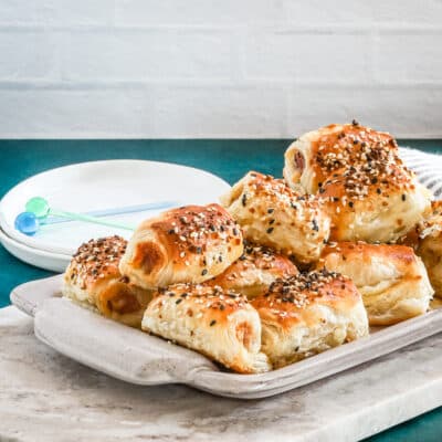 Puff pastry pigs in blankets on a serving tray with everything bagel seasoning.