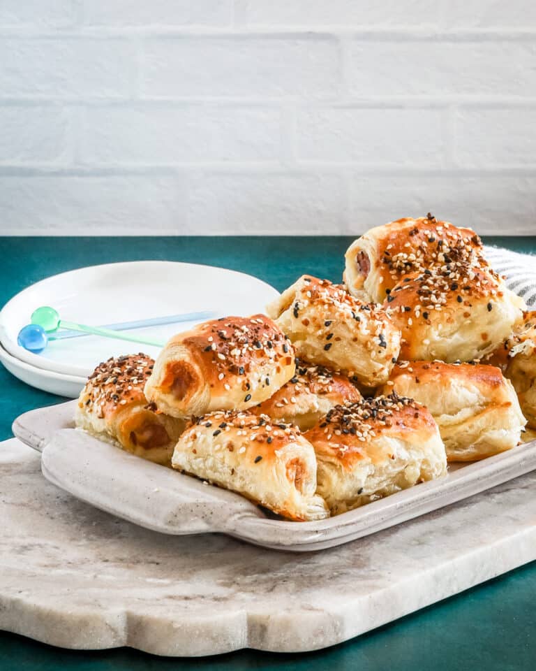 Puff pastry pigs in blankets on a serving tray with everything bagel seasoning.