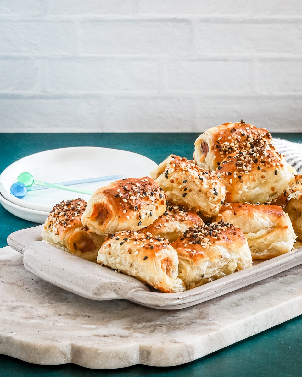 Puff pastry pigs in blankets on a serving tray with everything bagel seasoning.
