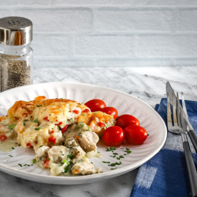 A serving of chicken pot pie casseroles with some tomatoes on the side.