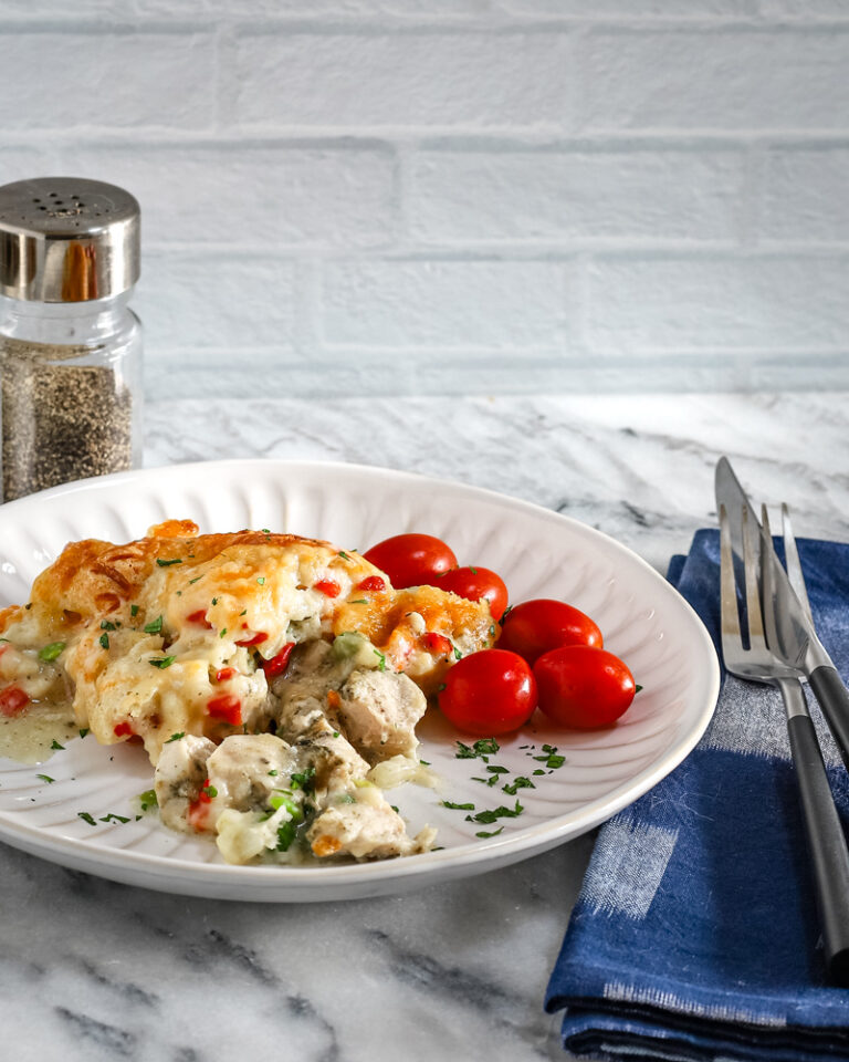 A serving of chicken pot pie casseroles with some tomatoes on the side.