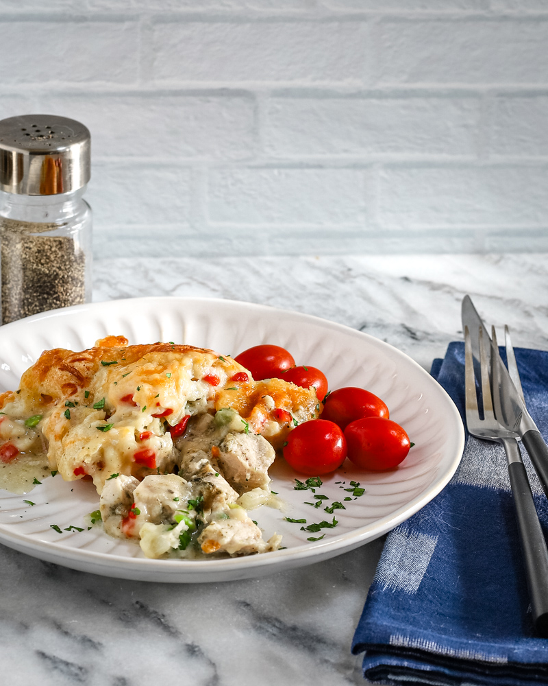 A serving of chicken pot pie casseroles with some tomatoes on the side.
