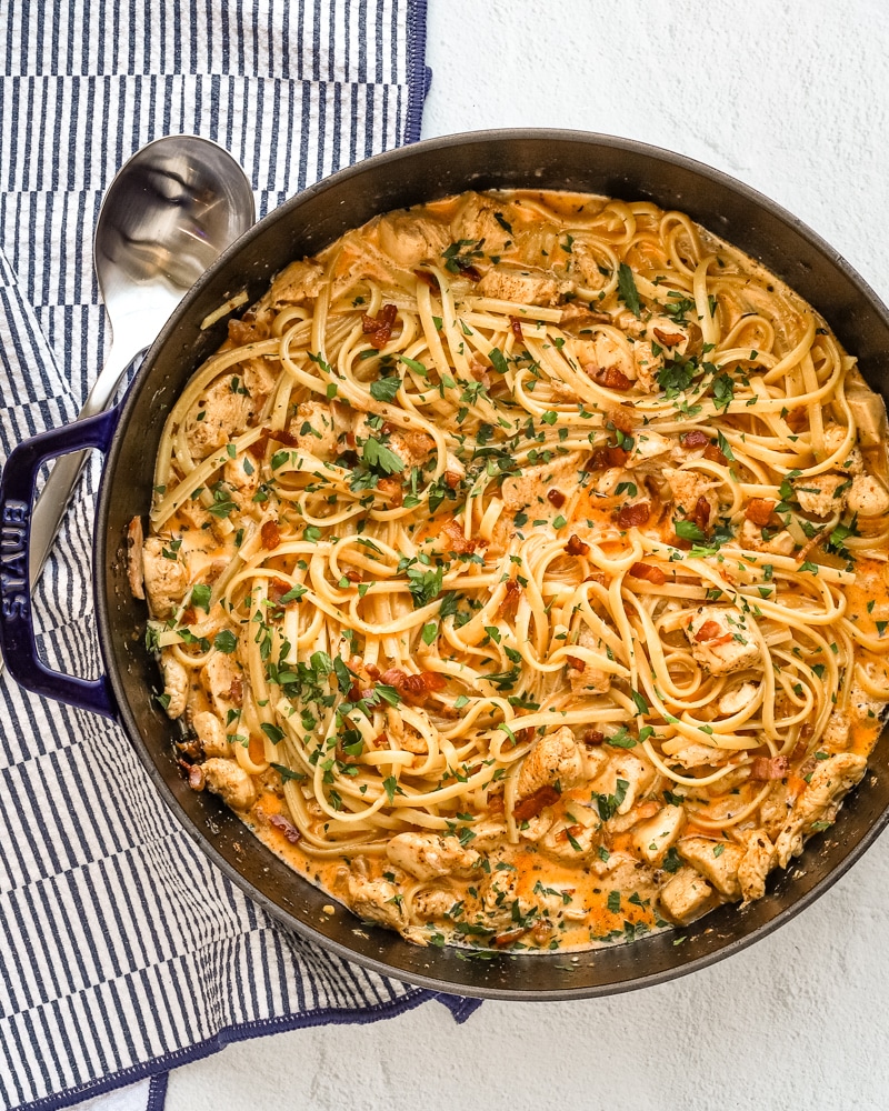 A pot of chicken and pasta with a spoon beside it.