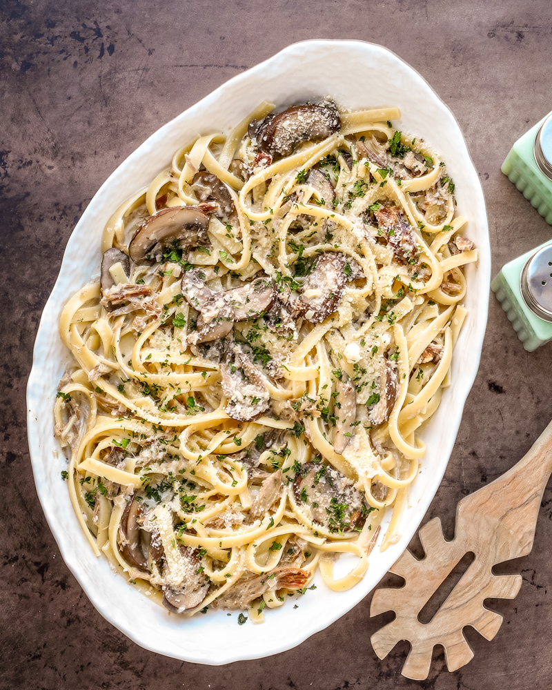 Pasta with duck confit and mushrooms in a serving bowl.