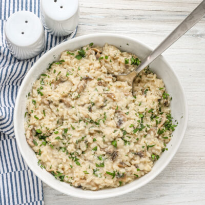 A bowl of Instant Pot mushroom risotto with a garnish of parsley and Parmesan cheese.
