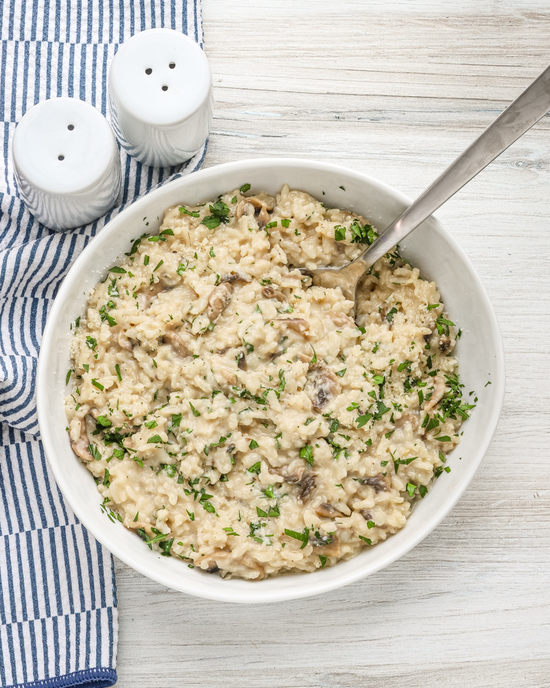 A bowl of Instant Pot mushroom risotto with a garnish of parsley and Parmesan cheese.