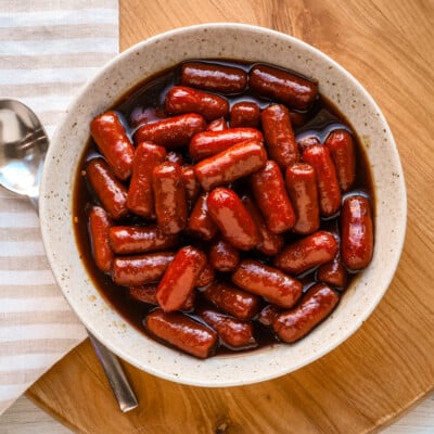 Sweet glazed little smokies with rich sauce in a white bowl.