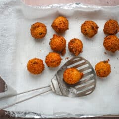 Freshly fried hush puppies from the fryer, draining on paper towels.