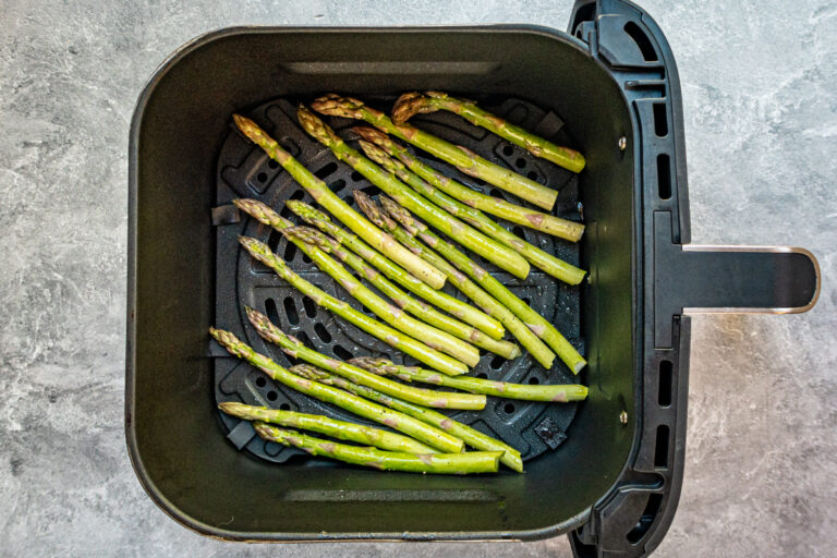 Roasted asparagus in air fryer basket.