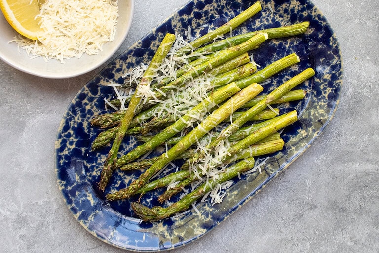 Fresh roasted asparagus with grated cheese and lemon slices.