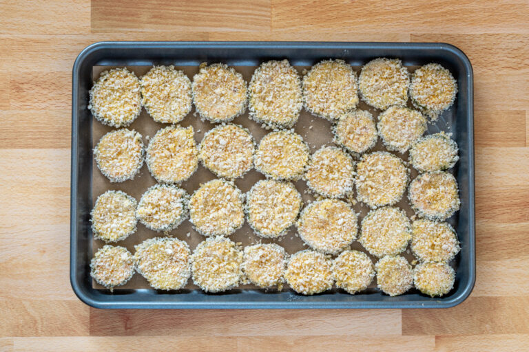 Breaded pickle slices on a sheet pan.