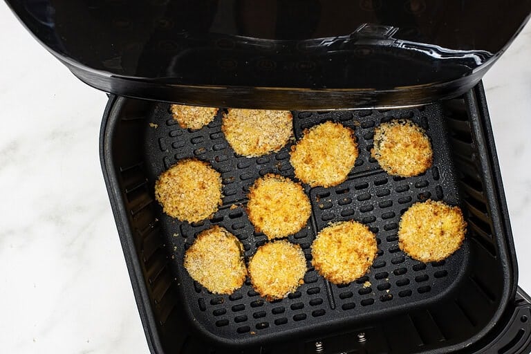 Air frying the breaded pickle slices.