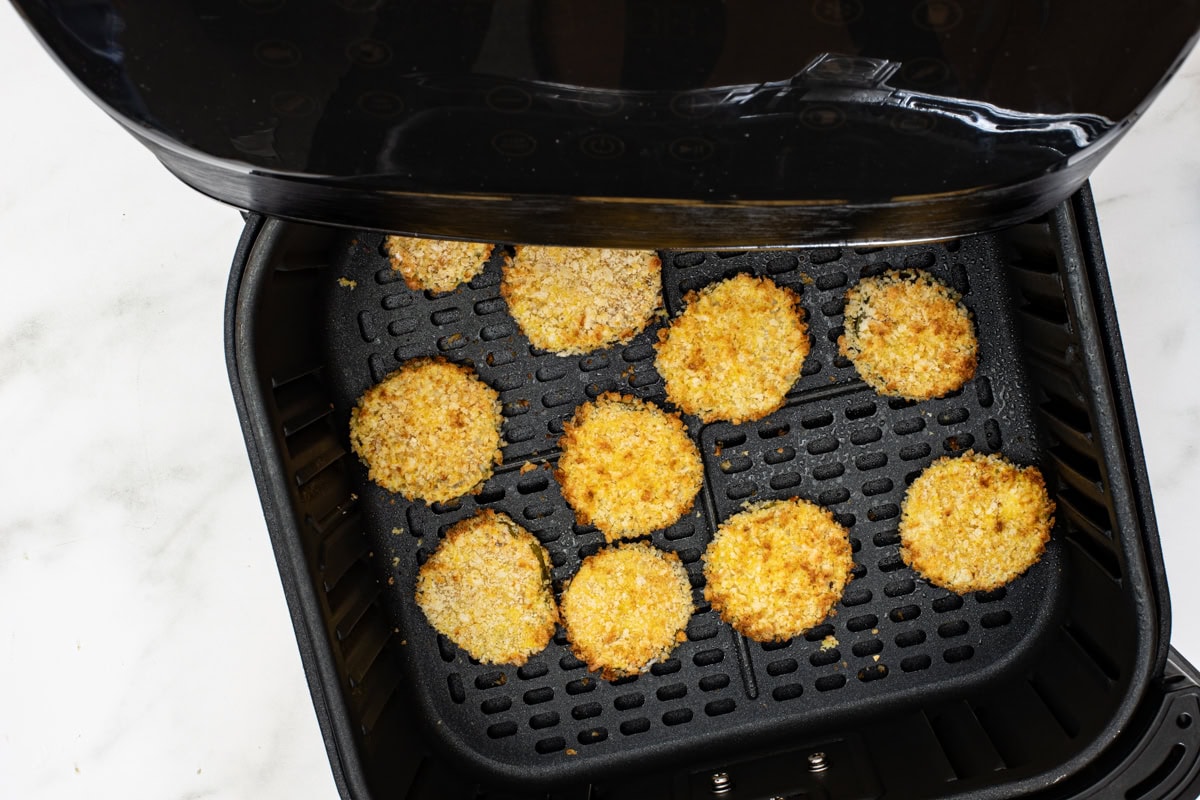 Air frying the breaded pickle slices.