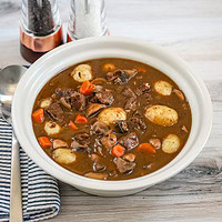 A bowl of beef Burgundy stew with baby potatoes, mushrooms, carrots, and beef cubes.