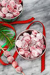 Sugared cranberries in small bowls with holiday decor.