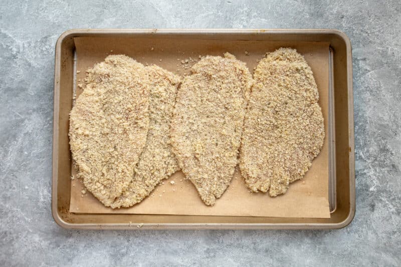The breaded chicken breast cutlets on a tray, ready to air-fry.