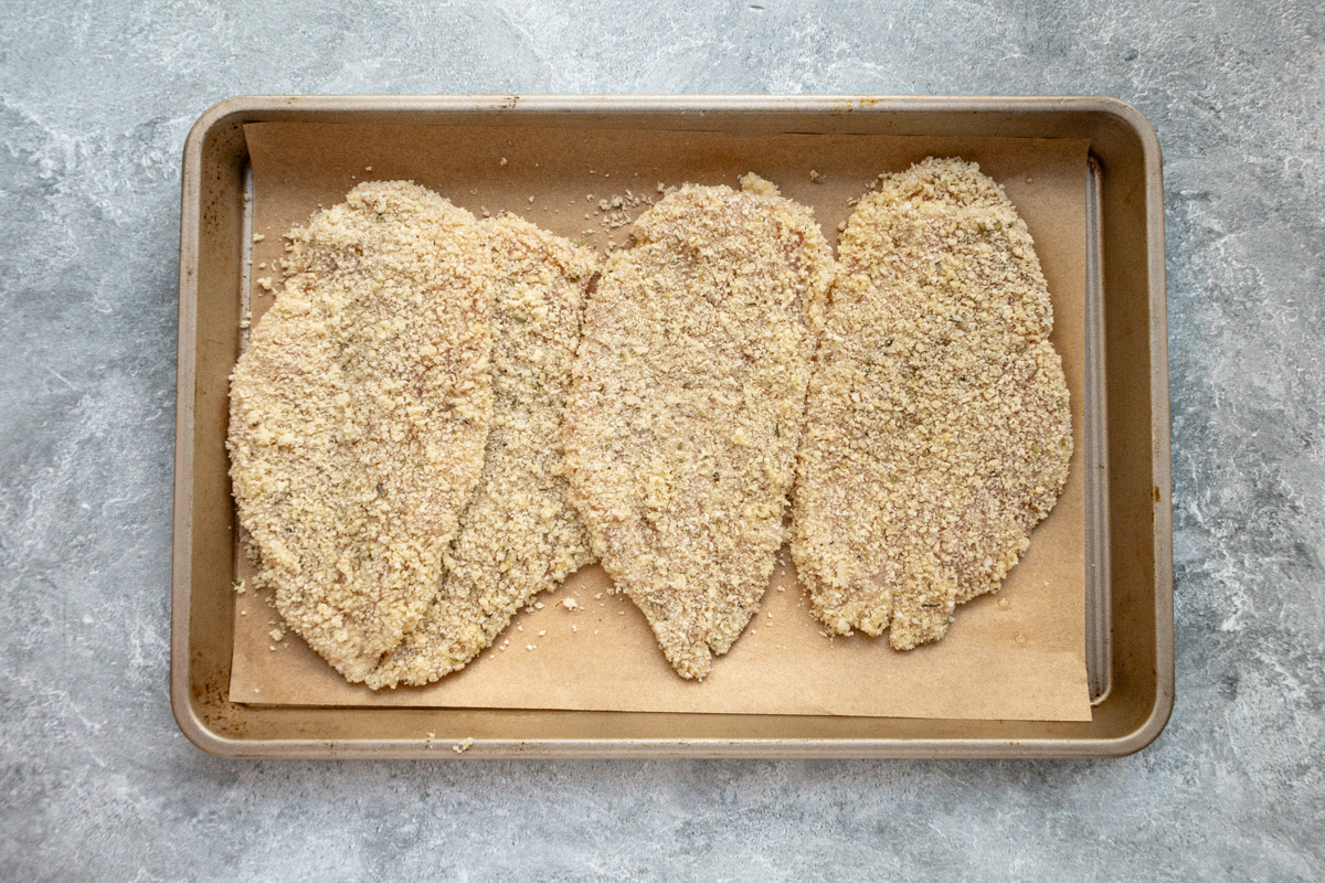The breaded chicken breast cutlets on a tray, ready to air-fry.