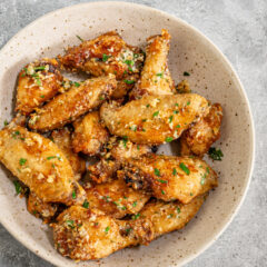 A serving bowl with air fryer garlic Parmesan chicken wings.