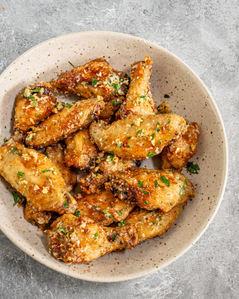 A serving bowl with air fryer garlic Parmesan chicken wings.