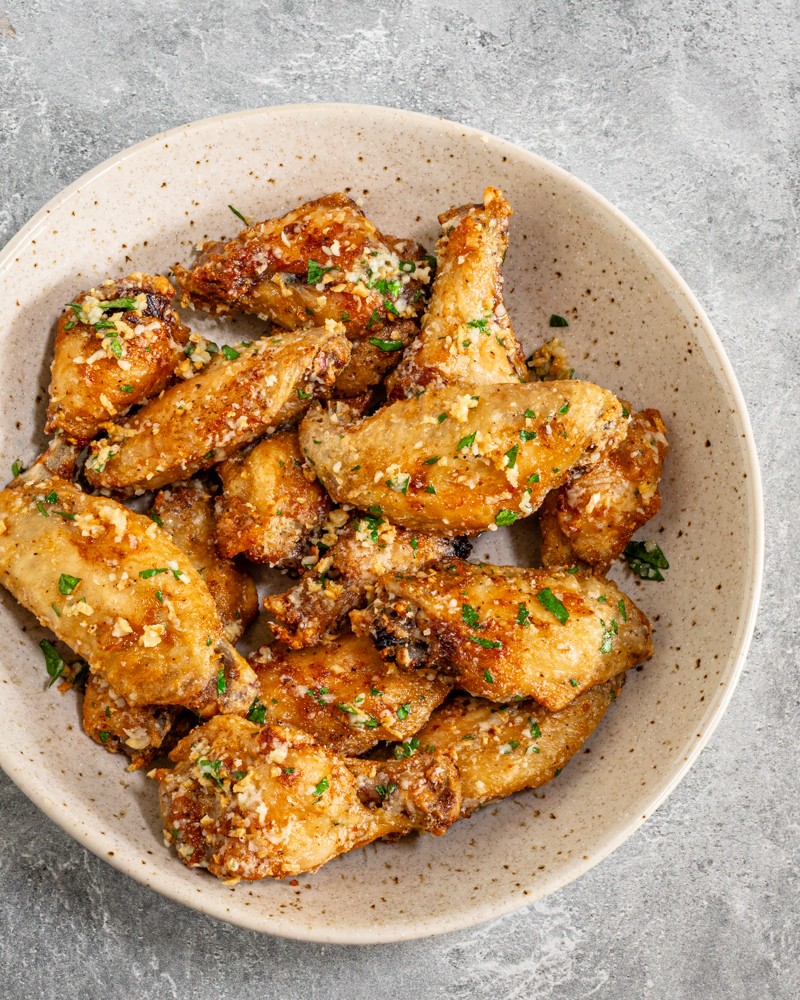 A serving bowl with air fryer garlic Parmesan chicken wings.