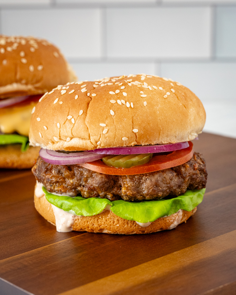 Juicy beef burgers with fresh vegetables and sesame seed buns.