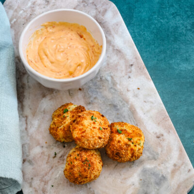 A plate of homemade air fryer potato croquettes made with leftover mashed potatoes, cheese, and herbs, and a dip on the side